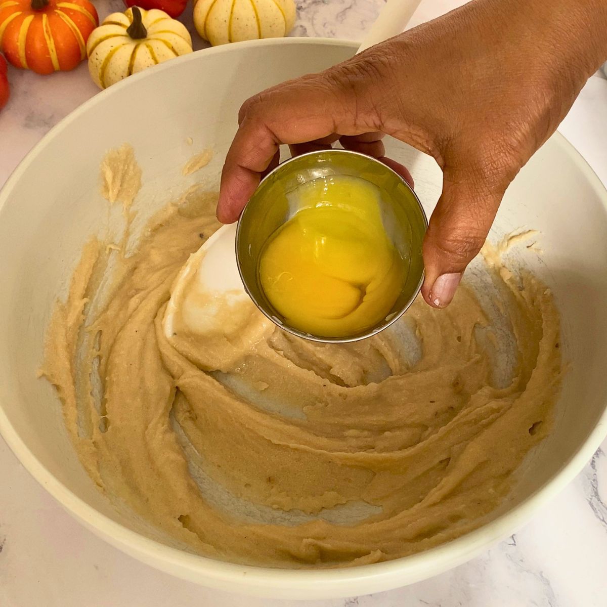 Adding egg yolk to the pumpkin chocolate chip cookies.