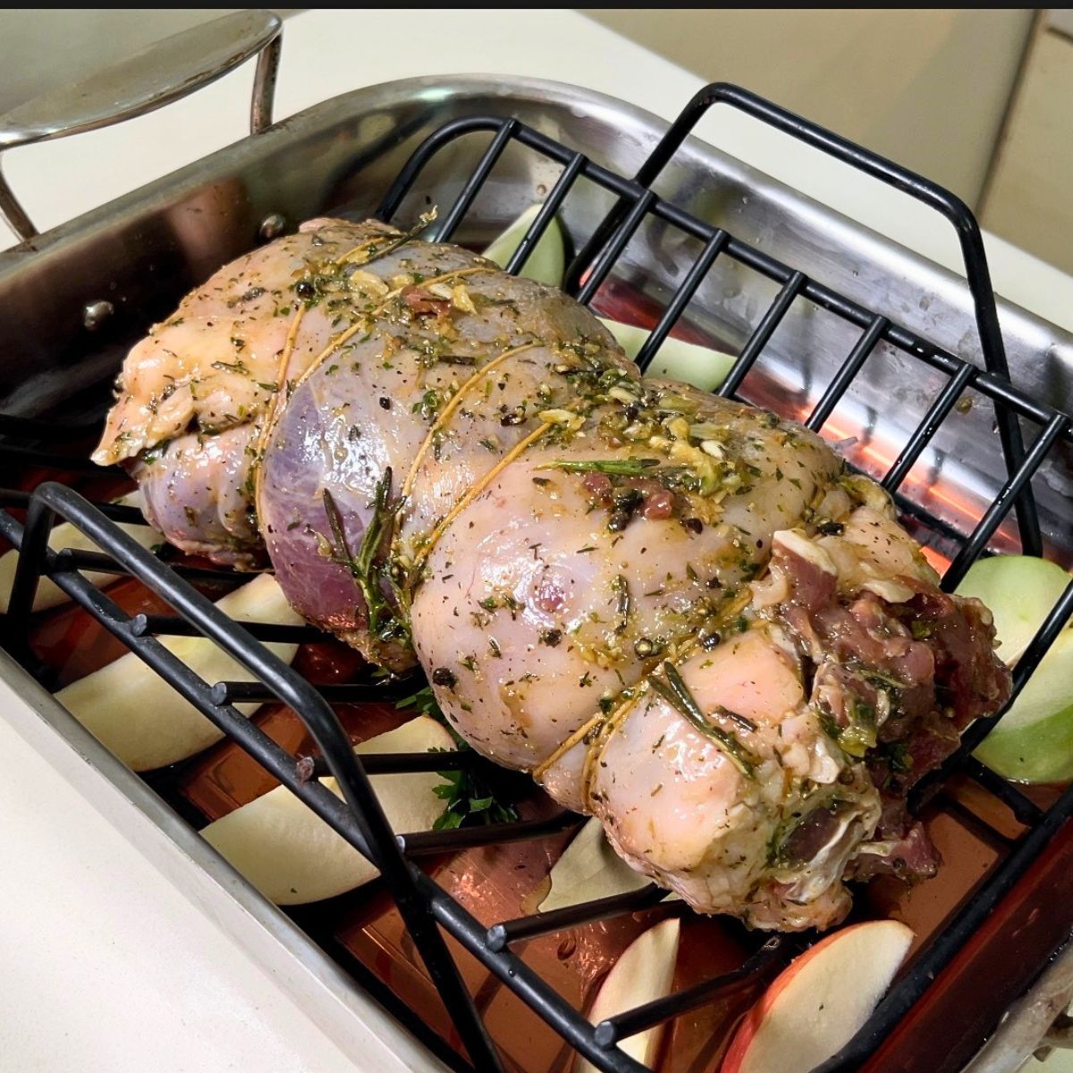 Boneless lamb tied with twine in a roasting rack.