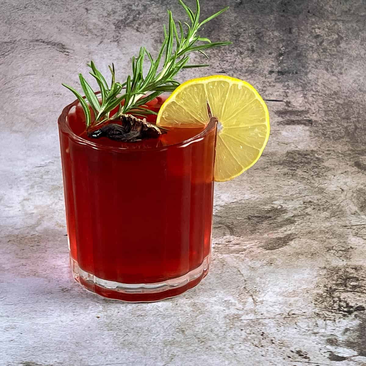 A glass with deep red cocktail made with hibiscus.