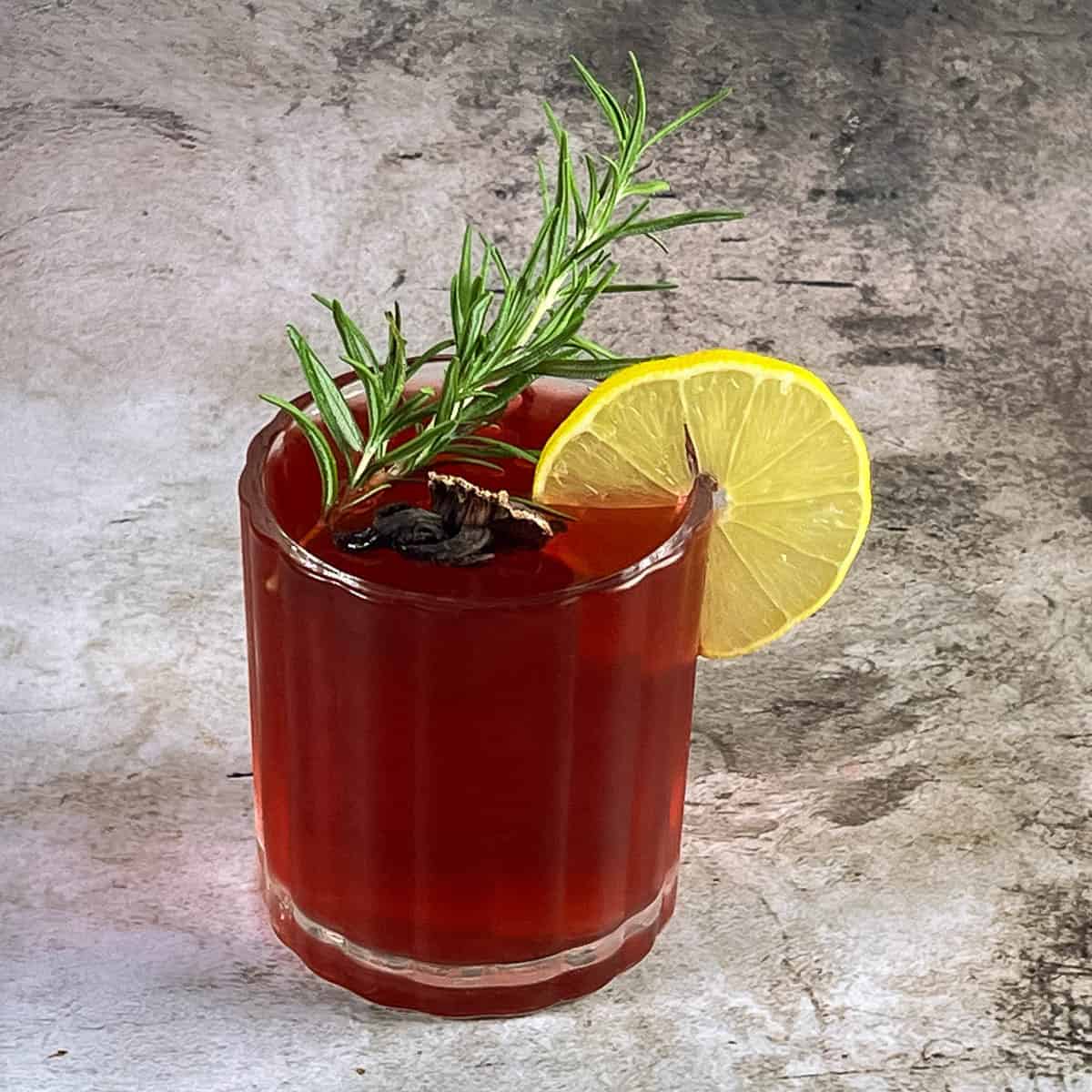 A glass with deep red cocktail made with hibiscus.