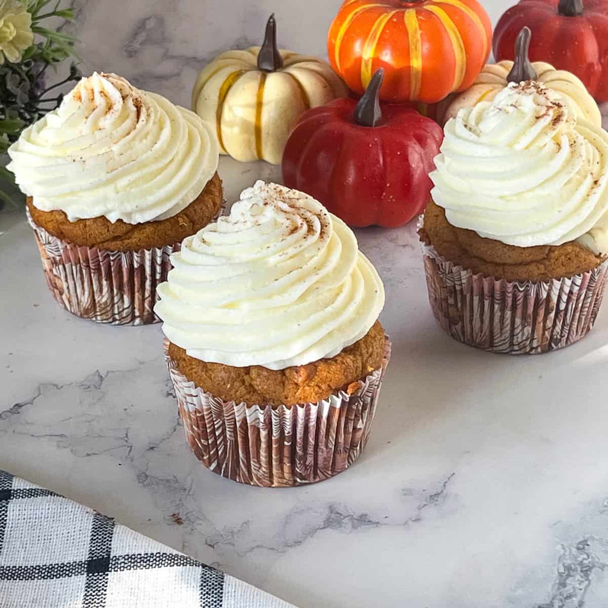 Frosted pumpkin cupcakes on the table.