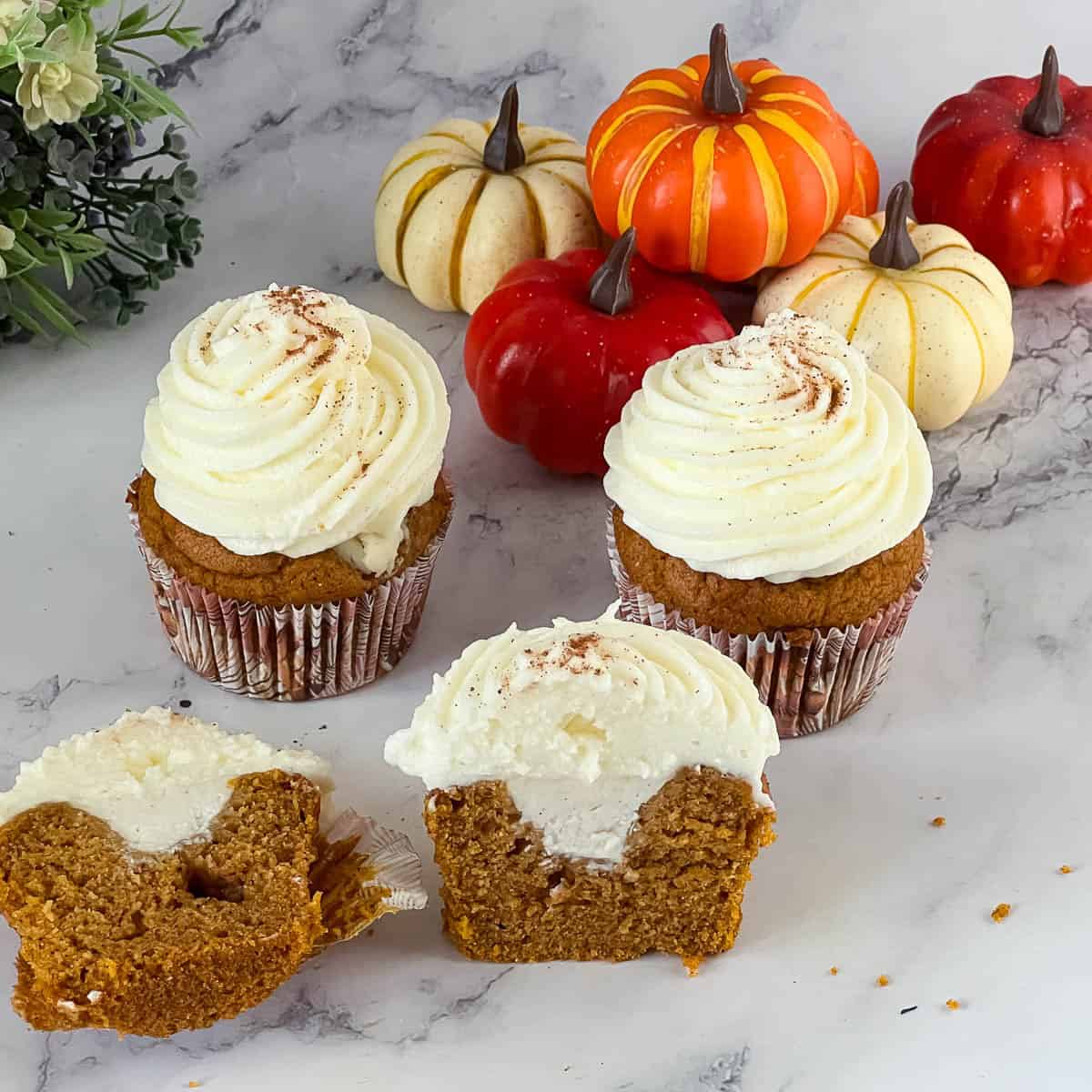 Pumpkin cupcakes with cream cheese filling on the table.