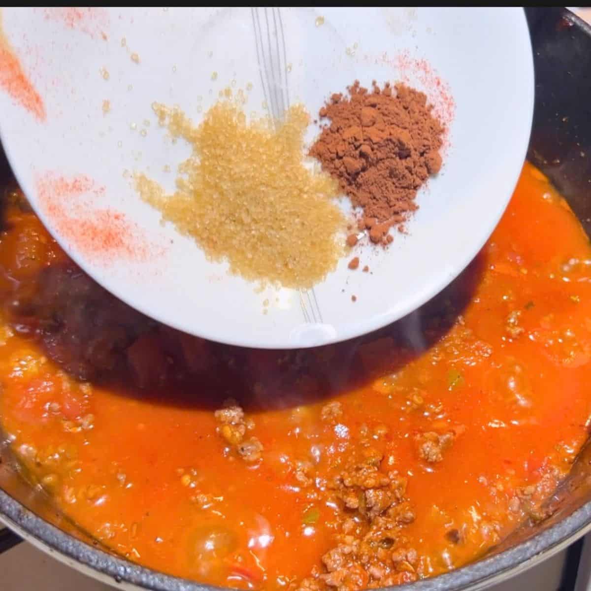 Adding brown sugar and cocoa powder to the chili recipe.