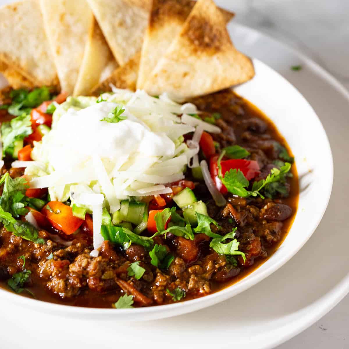 A white bowl with ground beef and beans soup.